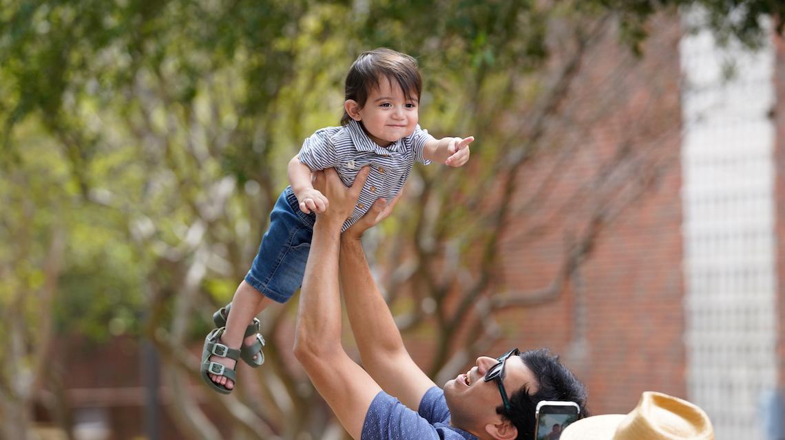 在返校节活动中，一位家长将他的孩子举在空中